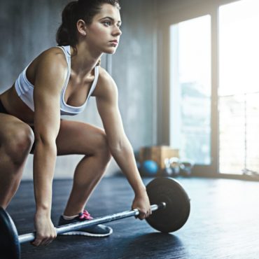 Shot of a sporty young woman working out with a barbell at the gym